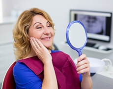 dental patient admiring her new smile in a mirror 