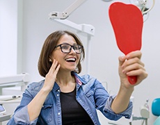 young woman admiring her new dental implants in Framingham