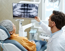 Smiling dentist reviewing X-ray with patient during consultation