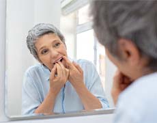 Woman flossing as part of her dental implant care in Framingham