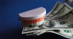 a model of teeth biting down on cash