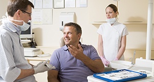 Man in dental chair talking to his dentist
