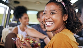 Woman smiling while eating well-balanced meal on road trip