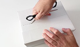 Man using scissors to open white box