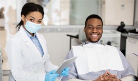 Patient and dentist smiling while sitting in treatment room