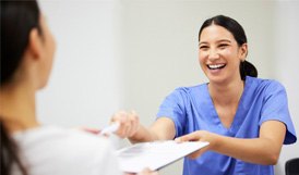 Dental assistant smiling while handing patient form