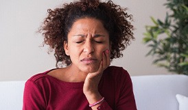 Woman with toothache sitting on couch at home