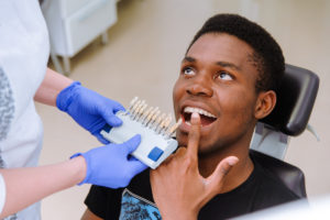 Man's smile compared with tooth color chart