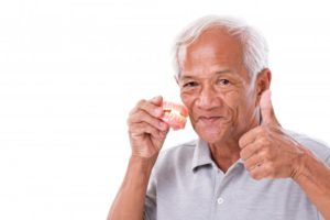 Man holding dentures gives thumbs up to denture care tips