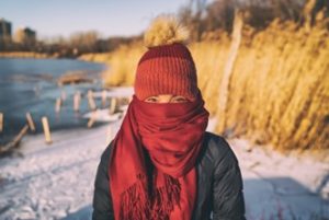 Woman standing outside wearing scarf wrapped over her mouth and nose