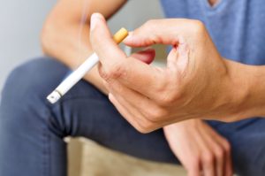 Man with dental implants holding a cigarette 