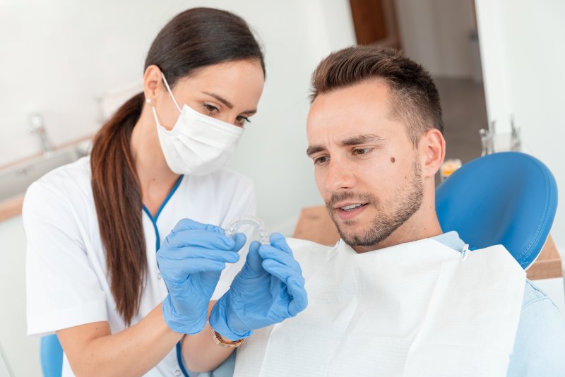 Dentist showing patient Invisalign trays