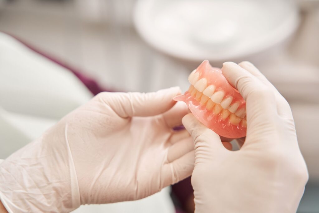 Hands in white gloves holding complete set of dentures